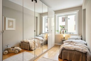 Spiegelkast die een compacte slaapkamer optisch verdubbelt voor een ruimtelijk effect.